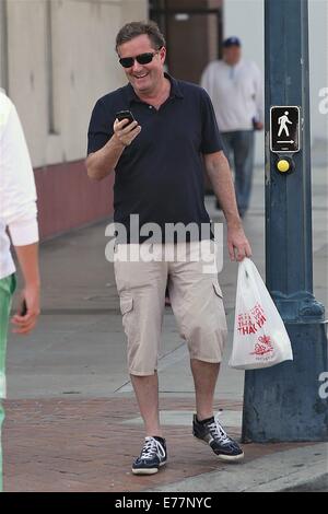 Piers Morgan 3/4 Länge tragen shorts wartet, überqueren Sie die Straße mit seinem Imbiss in einer Plastiktüte, während der Einnahme eines Anrufs auf seinem Handy mit Telefon: Piers Morgan Where: Los Angeles, California, Vereinigte Staaten von Amerika bei: 6. März 2014 Stockfoto