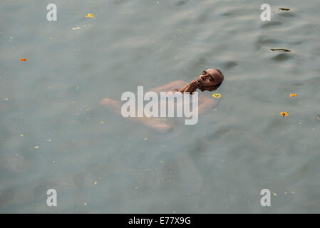 Ein Mann tritt Padmasana, Lotussitz, Baden im heiligen Wasser des Flusses Godwari, Nasik, Maharashtra, Indien Stockfoto