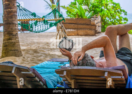 Ein Mann liest ein e-Book am Strand