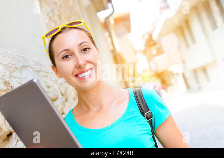 Mädchen auf der Straße lächelt und hält Tablet-computer Stockfoto