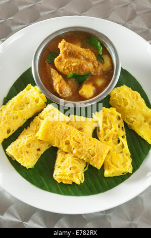 Roti Jala mit Kari Ayam. Lacy Pfannkuchen mit Hühnchen-Curry. Malaysia-Essen Stockfoto