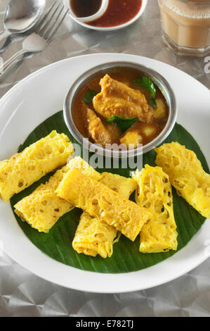 Roti Jala mit Kari Ayam. Lacy Pfannkuchen mit Hühnchen-Curry. Malaysia-Essen Stockfoto