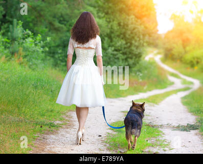 Junge Braut Wandern mit Hund auf der Landstraße Stockfoto