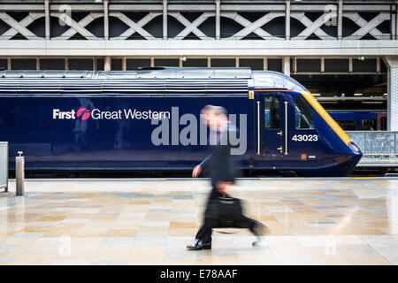 Ein Geschäft Pendler Spaziergänge übergeben einen stationären erstes Great Western Intercity Zug am Bahnhof Paddington in London, England, UK Stockfoto