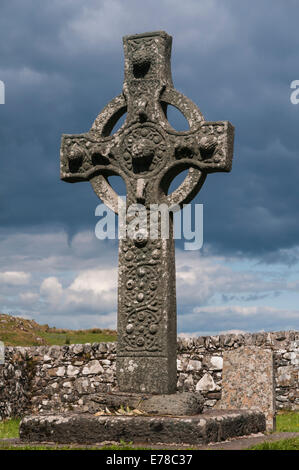 Kildalton Cross, beleuchtet durch Sonnenschein gegen einen dunklen und düsteren Himmel, auf der Isle of Islay, Inneren Hebriden, Schottland. Stockfoto