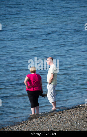 Aberystwyth, Wales, UK. 9. September 2014.  Wie das Vereinigte Königreich in einen längeren Zeitraum warmes sonniges Wetter, ein paar, Mann und Frau sonnt, Paddeln im Meer die Sonne am Strand in Aberystwyth zu genießen.   Temperaturen, die heute in dieser 'Indian Summer' bei 21ºc in London und Cardiff erreichte Bildnachweis: Keith Morris / Alamy Live News Stockfoto