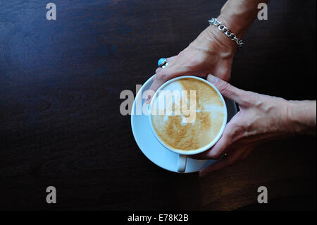 Reife Frau in Café hält eine Tasse Kaffee cappuccino Stockfoto
