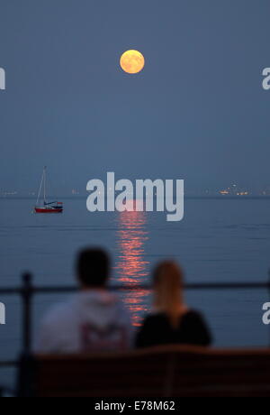 Swansea, Großbritannien. 9. September 2014.  Im Bild: ein paar auf einer Bank sitzend zu beobachten die Super Mond, bekannt als Perigäum über Swansea Bay aufgeht, wie gesehen von Mumbles, Süd-Wales, Vereinigtes Königreich. Bildnachweis: D Legakis/Alamy Live-Nachrichten Stockfoto