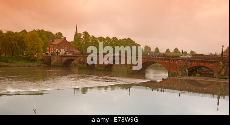 Ikonische gewölbte Brücke überquert den Fluss Dee in Chester mit Segment spiegelt sich in ruhigem Wasser unter rosa Abendhimmel