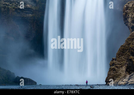 der einsame Figur von Wendy Stand am Fuße des Skógafoss, Süden Islands Stockfoto