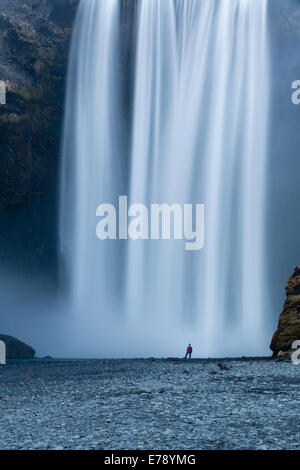 der einsame Figur von Wendy Stand am Fuße des Skógafoss, Süden Islands Stockfoto