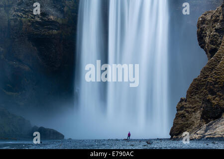 der einsame Figur von Wendy Stand am Fuße des Skógafoss, Süden Islands Stockfoto