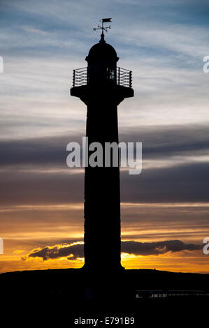 Der Leuchtturm auf der West Pier Silhouette gegen den Sonnenuntergang in Whitby, North Yorkshire. April. Stockfoto