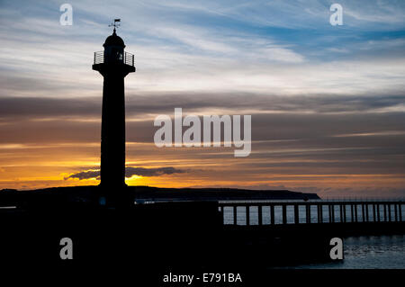 Der Leuchtturm auf der West Pier Silhouette gegen den Sonnenuntergang in Whitby, North Yorkshire. April. Stockfoto