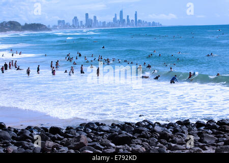 Surfer genießen die Wellen in Burleigh Heads an der Gold Coast in Australien.  Surfers Paradise ist in der Ferne. Stockfoto