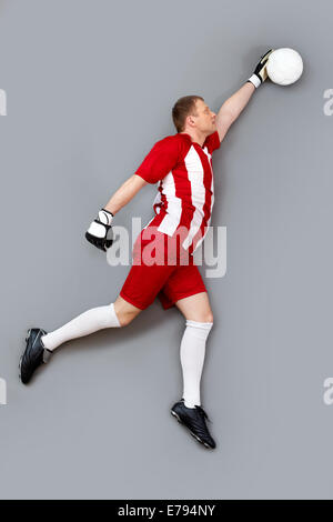 Torwart den Ball fängt, auf grauem Hintergrund Stockfoto