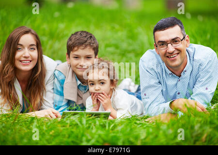 Entzückende Kinder und ihre Eltern verbringen Freizeit im freien Stockfoto