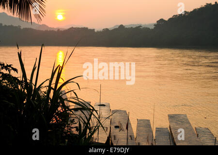 Die Sonne beginnt, über den dichten Dschungel gesetzt, wie ein weiterer Tag in Luang Prabang zu einem Ende kommt. Stockfoto