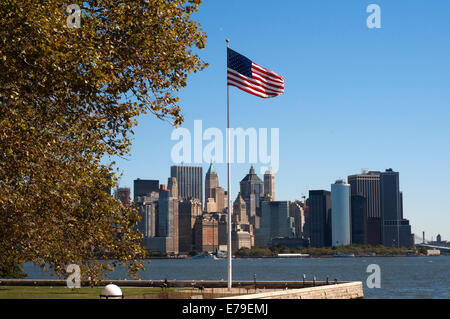 Amerikanische Flagge. Riesigen Wolkenkratzern Uferpromenade vom Battery Park und Pier A. Pier A im Battery Park ist ein Gebäude, erbaut 1886 durch die Abteilung des Docks und Fähren, teilweise renoviert noch einen trauriger Zustand präsentiert, es scheint, dass es ein Streit zwischen den Behörden und die Unternehmen hinter seiner Rehabilitation. Im vergangenen Frühjahr begrüßt Amelia Earhart, die Königin und verschiedene Staatsoberhäupter. Stockfoto