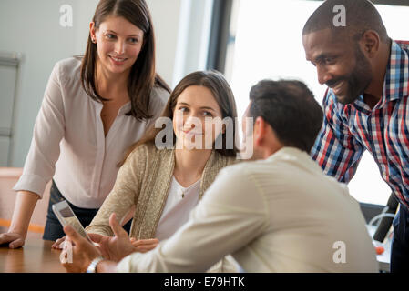 Vier Menschen, Männer und Frauen, gruppieren sich um einen digital-Tablette, Blick auf dem Bildschirm. Stockfoto