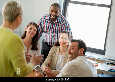 Fünf Menschen in einem Büro, zwei Männer und drei Frauen reden. Stockfoto