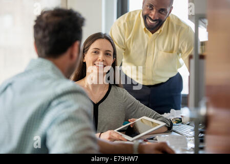 Drei Menschen in einem Büro, zwei Männer und eine Frau mit Computer-Monitor und digital-Tablette. Stockfoto