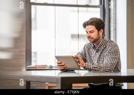 Büroalltag. Ein Mann auf einem digitalen Tablet an einem Schreibtisch arbeiten. Stockfoto