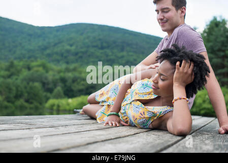 Ein paar entspannende auf einem Steg mit Blick auf einen Bergsee. Stockfoto