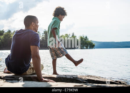 Vater und Sohn am Ufer eines Sees im Sommer. Stockfoto