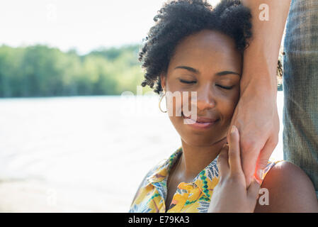 Eine Frau hält die Hand einer Person auf ihre Wange und lächelnd. Stockfoto