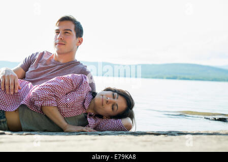 Ein paar entspannende, liegend auf einem hölzernen Steg an einem See im Sommer. Stockfoto