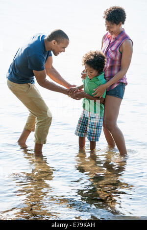 Familie, Mutter, Vater und Sohn spielen am Ufer eines Sees. Stockfoto