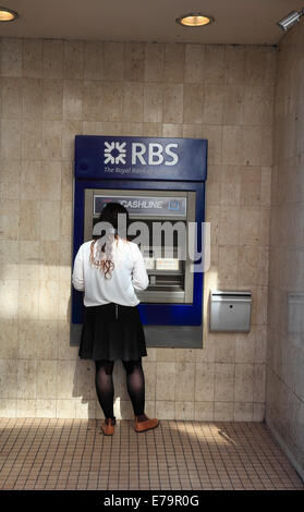 Eine junge Frau zieht Geld aus einer RBS-Geldautomat. Stockfoto