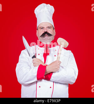 strenge Koch holding Messer und Schneebesen Stockfoto
