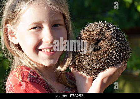 lächelndes Mädchen mit niedlichen Igel-Ball in Hand Stockfoto