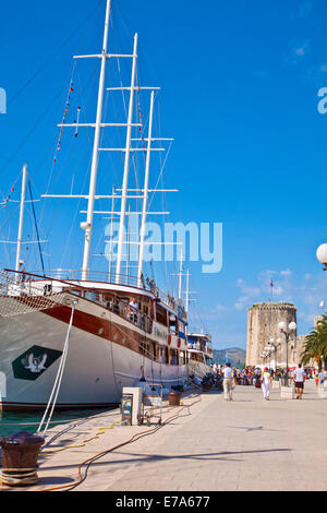 Kroatien, Trogir: Touristen auf das Meer promenade mit touristischen Kreuzfahrtschiffe vor Anker und die Aussicht auf die Burg Turm Kamerlengo Stockfoto