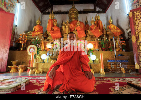 Ein Mönch im Lotussitz vor goldenen Buddhas meditieren Stockfoto