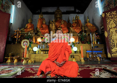 Ein Mönch im Lotussitz vor goldenen Buddhas meditieren Stockfoto