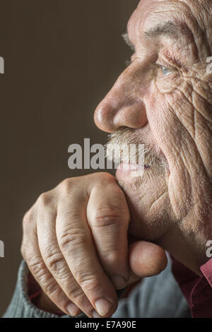 Nahaufnahme Seitenansicht des nachdenklichen älteren Mann mit Hand am Kinn auf braunem Hintergrund Stockfoto