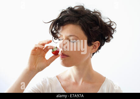 Eine Frau, die duftende Erdbeeren auf weißem Hintergrund Stockfoto
