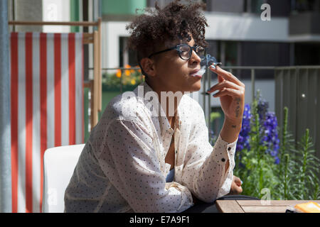 Junge Frau bei Veranda Rauchen Stockfoto