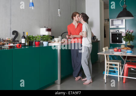 Volle Länge des romantischen schwules Paar küssen in der Küche Stockfoto
