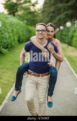 Mann und Frau Huckepack Fahrt im park Stockfoto