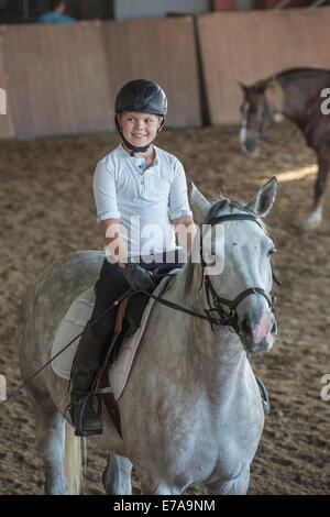 Junge auf Pferd im Ausbildungsstall Stockfoto