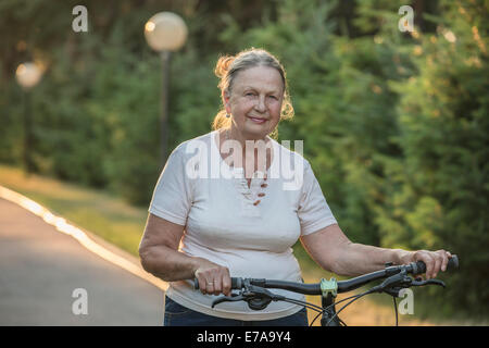 Portrait von senior Frau mit dem Fahrrad im park Stockfoto