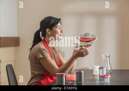 Nachdenkliche Frau Malerei Schale am Tisch im Haus Stockfoto