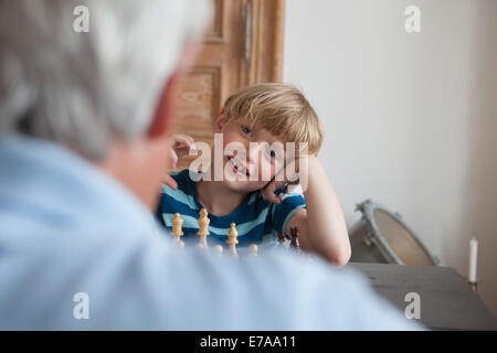 Fröhlicher Junge spielt Schach mit Großvater zu Hause Stockfoto