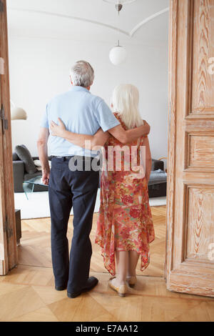Voller Länge Rückansicht des älteres paar stehend mit Arme um am Eingang im Haus Stockfoto