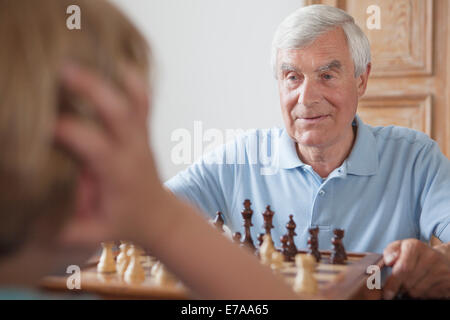Ältere Mann spielt Schach mit Enkel zu Hause Stockfoto
