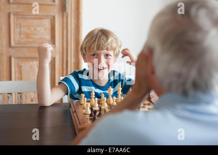 Glücklich Enkel spielt Schach mit Großvater zu Hause Stockfoto